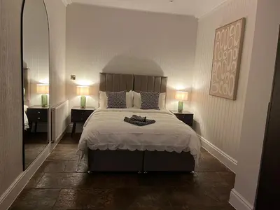 a bedroom with a large bed with two lamps on both sides at The Croft Farmhouse Apartments in East Horndon
