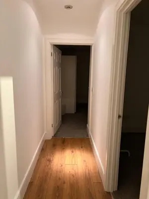 an empty hallway with white walls and wood floors at The Croft Farmhouse Apartments in East Horndon