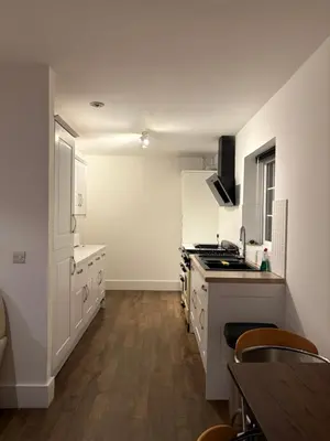 a kitchen with white cabinets and a wooden floor at The Croft Farmhouse Apartments in East Horndon