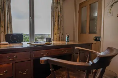 a desk with a chair in front of a window at 1 Box Iron Cottage, Shotley in Shotley