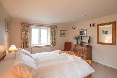 a bedroom with a large white bed and a window at 1 Box Iron Cottage, Shotley in Shotley