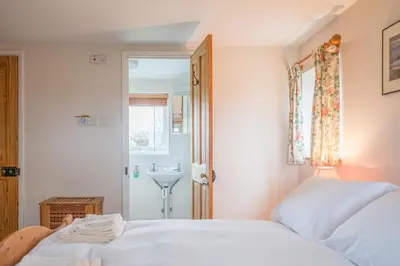a bedroom with a bed and a sink and a window at 1 Box Iron Cottage, Shotley in Shotley