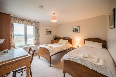 two beds in a room with a desk and a window at 1 Box Iron Cottage, Shotley in Shotley