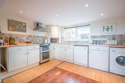 a kitchen with white cabinets and a washer and dryer at 1 Box Iron Cottage, Shotley in Shotley
