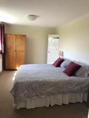 a bedroom with a large bed with red pillows at Acreland Green in Pleshey