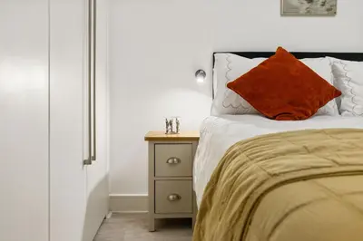 a bed with an orange pillow and a night stand at Khayat Homes - The Ford in Chelmsford