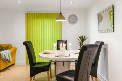 a dining room with a table and green curtains at Khayat Homes - The Ford in Chelmsford