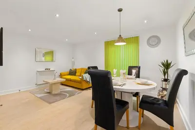 a living room with a table and a yellow couch at Khayat Homes - The Ford in Chelmsford