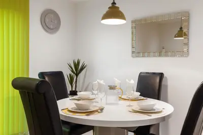 a white table with black chairs and a mirror at Khayat Homes - The Ford in Chelmsford