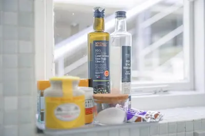 a shelf with a bottle of alcohol and other ingredients at Central Victorian Villa 2 Floor I Parking I Garden in Cambridge