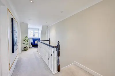 a white hallway with a staircase with a blue chair at Luv home with pool and cinema room