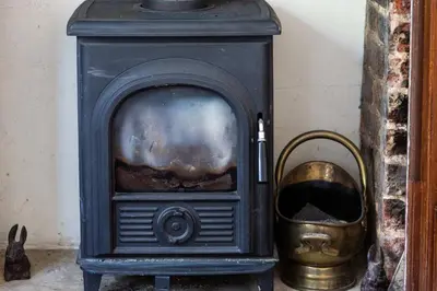 a black stove with a gold bucket next to it at 5 Bed Seaside Property with Garden , Parking and Games Room in Southend-on-Sea
