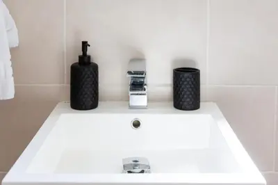 a white bathroom sink with two black containers on it at 5 Bed Seaside Property with Garden , Parking and Games Room in Southend-on-Sea