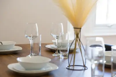 a wooden table with wine glasses and a vase on it at 5 Bed Seaside Property with Garden , Parking and Games Room in Southend-on-Sea