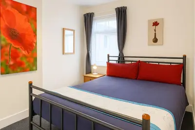 a bedroom with a bed with red pillows and a window at 1 Bed Service Accommodation- contractor ready in Southend-on-Sea
