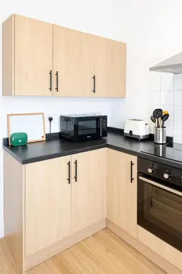 a kitchen with wooden cabinets and a black counter top at 1 Bed Service Accommodation- contractor ready in Southend-on-Sea