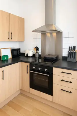 a kitchen with wooden cabinets and a stove top oven at 1 Bed Service Accommodation- contractor ready in Southend-on-Sea