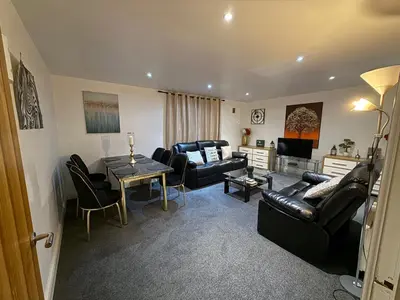 a living room with black leather furniture and a table at Guildford Court Apartment in Colchester in Colchester