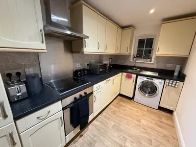 a kitchen with white cabinets and a washer and dryer at Guildford Court Apartment in Colchester in Colchester