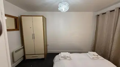 a small bedroom with a bed and a cabinet at Guildford Court Apartment in Colchester in Colchester