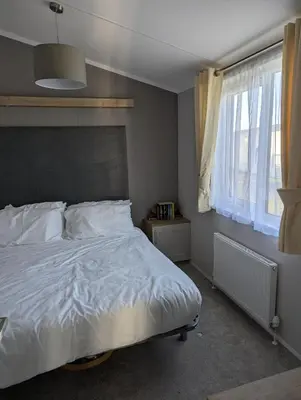 a bedroom with a white bed with a large window at Modern 6 Berth Caravan With Decking At Suffolk Sands Ref 45004F in Felixstowe