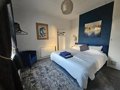 a bedroom with a large bed with a blue wall at Station House in Roudham
