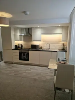 a kitchen with white cabinets and a table and chairs at Cosy Central 1-Bed with Parking & Wi-Fi in Ipswich