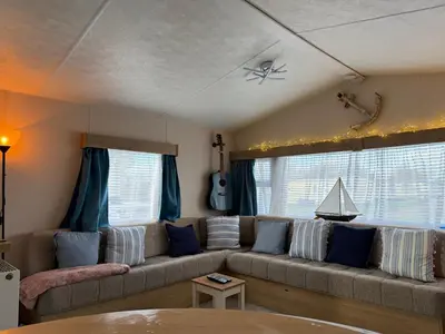 a living room with a couch and a guitar at Coastal Beachfront Caravan in Brightlingsea