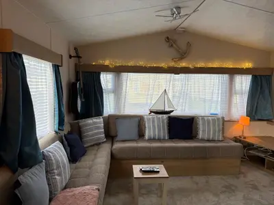 a living room with a couch and a table at Coastal Beachfront Caravan in Brightlingsea