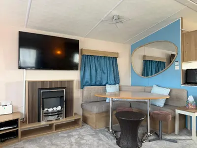a caravan living room with a table and a tv at Coastal Beachfront Caravan in Brightlingsea