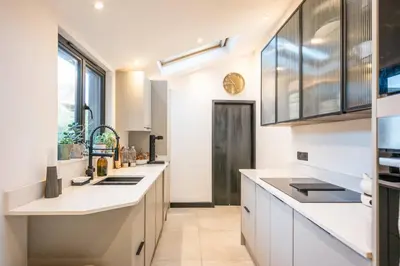 a kitchen with white counters and a large window at 9 Chantry Road, Saxmundham in Saxmundham