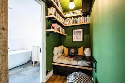 a bathroom with a green wall with a couch and bookshelves at 9 Chantry Road, Saxmundham in Saxmundham