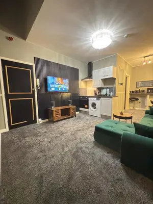 a living room with a green couch and a tv at The Olive Stay by Cambridge City Centre in Chesterton