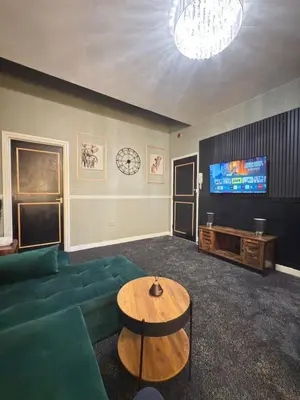 a living room with a green couch and a television at The Olive Stay by Cambridge City Centre in Chesterton