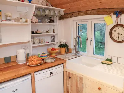 a kitchen with a sink and a clock on the wall at The Hare & The Bumblebee Cottage in Eye