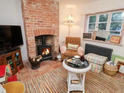 a living room with a brick fireplace and a couch at The Hare & The Bumblebee Cottage in Eye