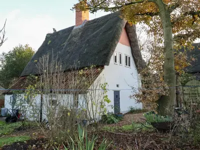 an old white house with a thatched roof at The Hare & The Bumblebee Cottage in Eye