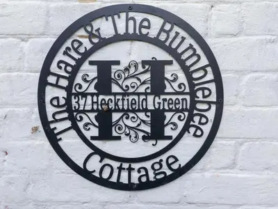 a black and white sign on a white brick wall at The Hare & The Bumblebee Cottage in Eye