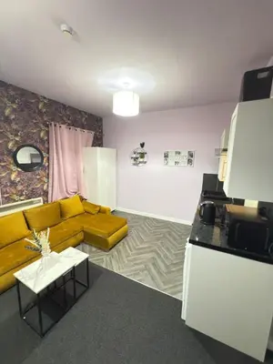 a living room with a yellow couch and a kitchen at The Lavender Stay by Cambridge City Centre in Chesterton