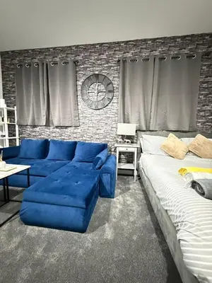 a living room with a blue couch and a bed at The Charcoal Stay by Cambridge City Centre in Chesterton