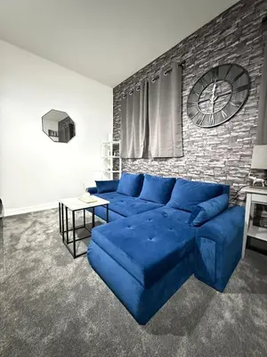 a blue couch in a living room with a brick wall at The Charcoal Stay by Cambridge City Centre in Chesterton