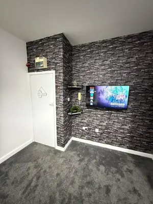 a room with a tv on a brick wall at The Charcoal Stay by Cambridge City Centre in Chesterton