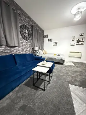 a living room with a blue couch and a brick wall at The Charcoal Stay by Cambridge City Centre in Chesterton