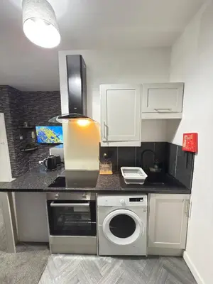 a kitchen with a counter with a washing machine at The Charcoal Stay by Cambridge City Centre in Chesterton