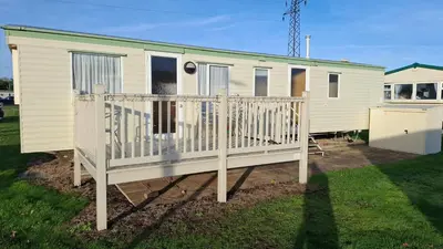 a mobile home with a porch and a fence at Suntrail House in Great Clacton