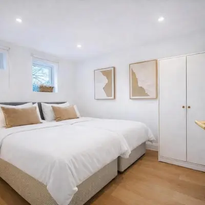 a white bedroom with a large bed and a cabinet at Spacious 2BR Designer Home in Newmarket , Private Grounds & Garden in Newmarket