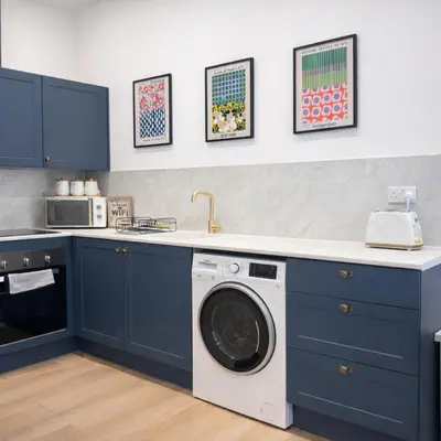 a kitchen with blue cabinets and a washer and dryer at Spacious 2BR Designer Home in Newmarket , Private Grounds & Garden in Newmarket