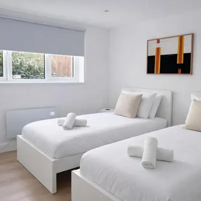 two beds in a room with white walls and windows at Spacious 2BR Designer Home in Newmarket , Private Grounds & Garden in Newmarket