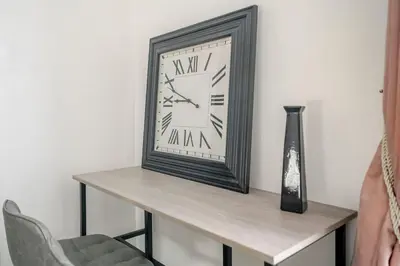a clock and a vase on a table with a chair at Keralia in Wivenhoe