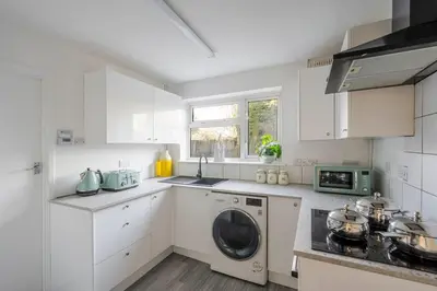 a kitchen with white cabinets and a washing machine at Keralia in Wivenhoe